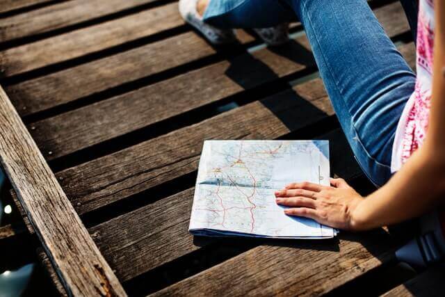 En pige der sidder med et verdenskort på en bro