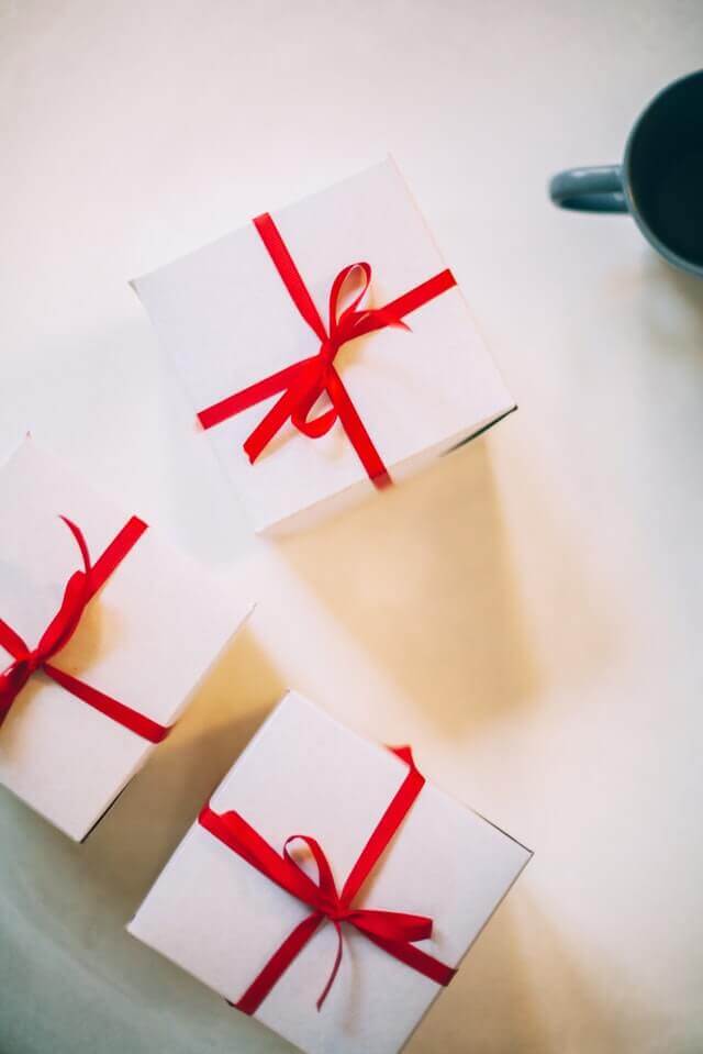 Tre gaver pakket ind i hvidt papir med en rød sløjfe omkring