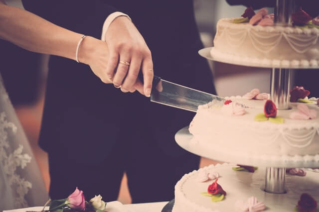 Et brudepar der er i færd med at skære bryllupskagen over, til deres bryllup